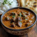 beef and coconut curry slow cooker in ceramic bowl with rice and naan
