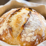 Bakery-Style Sourdough Bread 8 Freshly baked bakery-style sourdough bread loaf with golden crust on wooden board