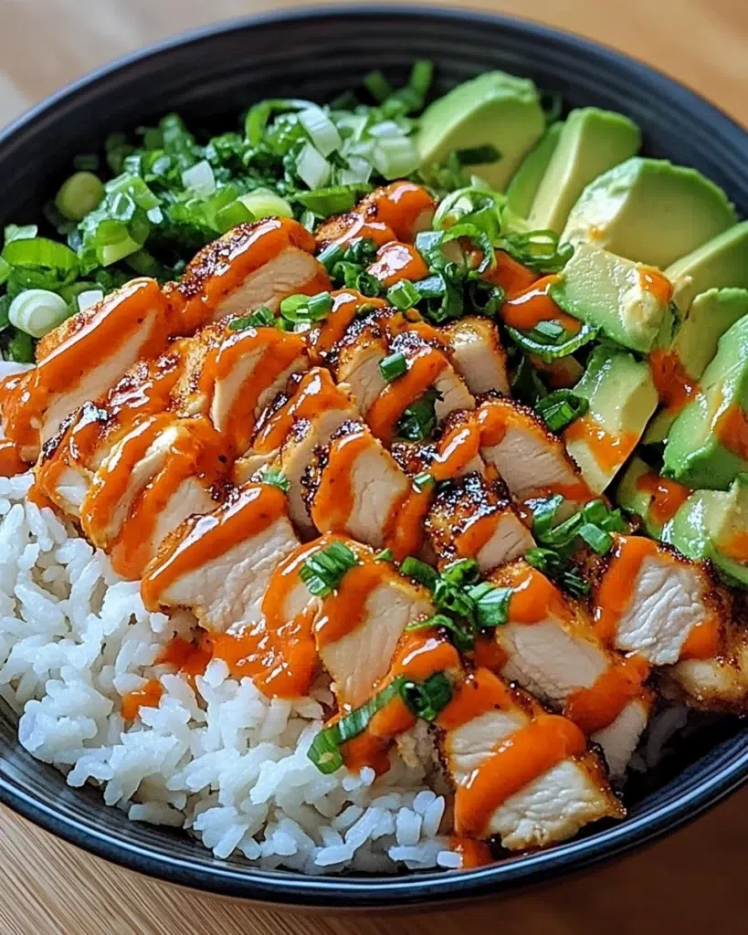 Bang Bang Chicken Bowl with tender chicken, crisp cabbage, cucumber, avocado, and creamy sauce in a white ceramic bowl.