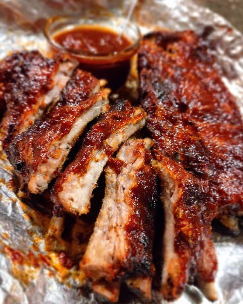 Sticky crockpot ribs glazed with BBQ sauce served on a wooden platter.